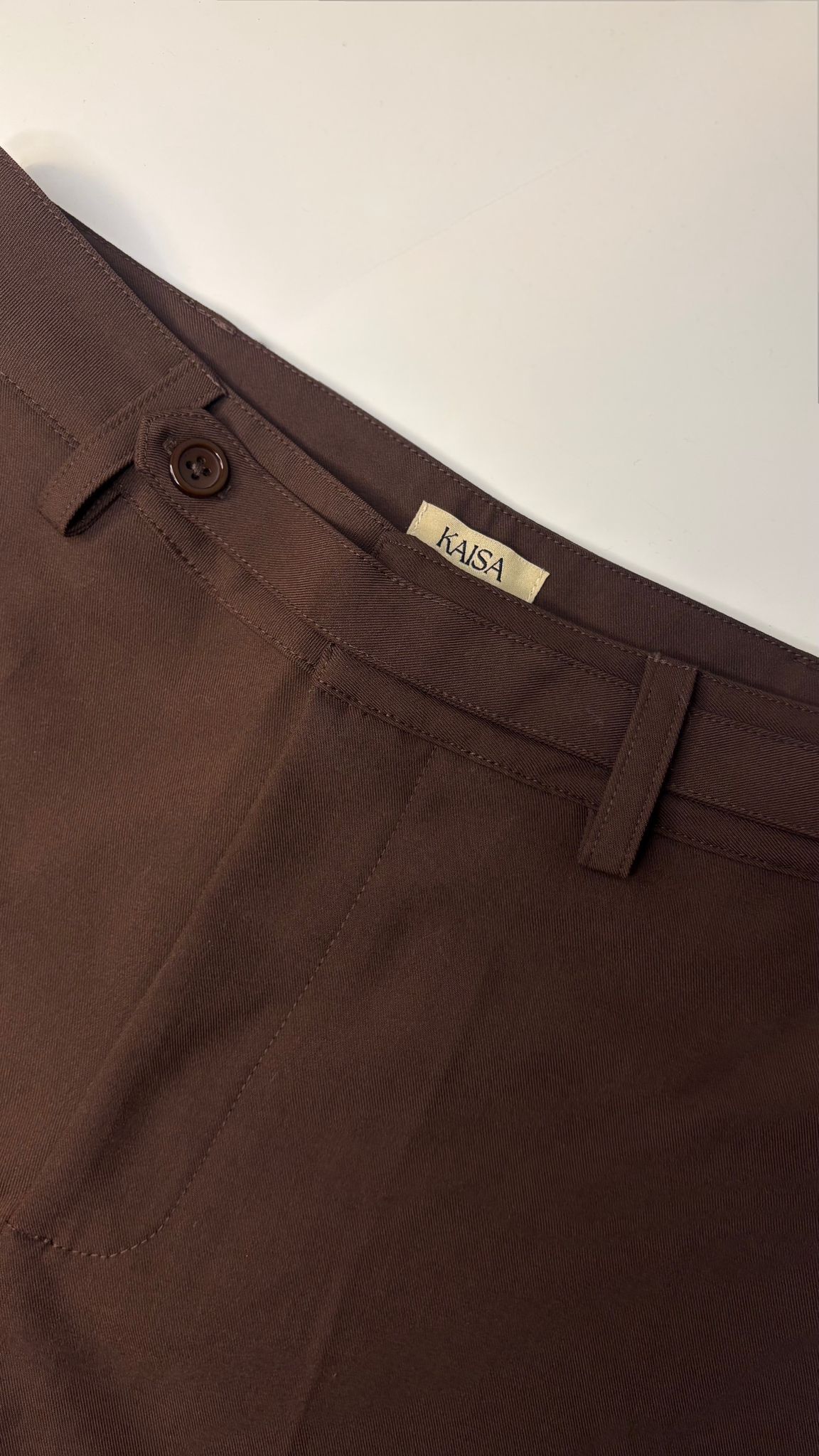 Close-up of Muse straight leg trousers in coffee brown showing waistband, button fastening and KAISA inside logo label