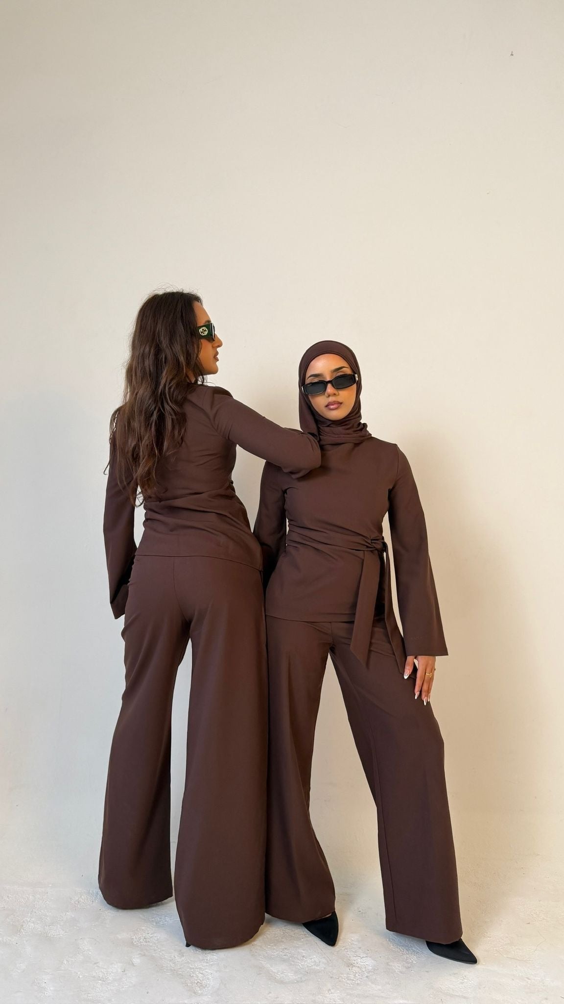 Two models, one facing forwards and the other facing backwards, wearing Muse straight leg trousers in coffee brown, tailored fit for petite frames