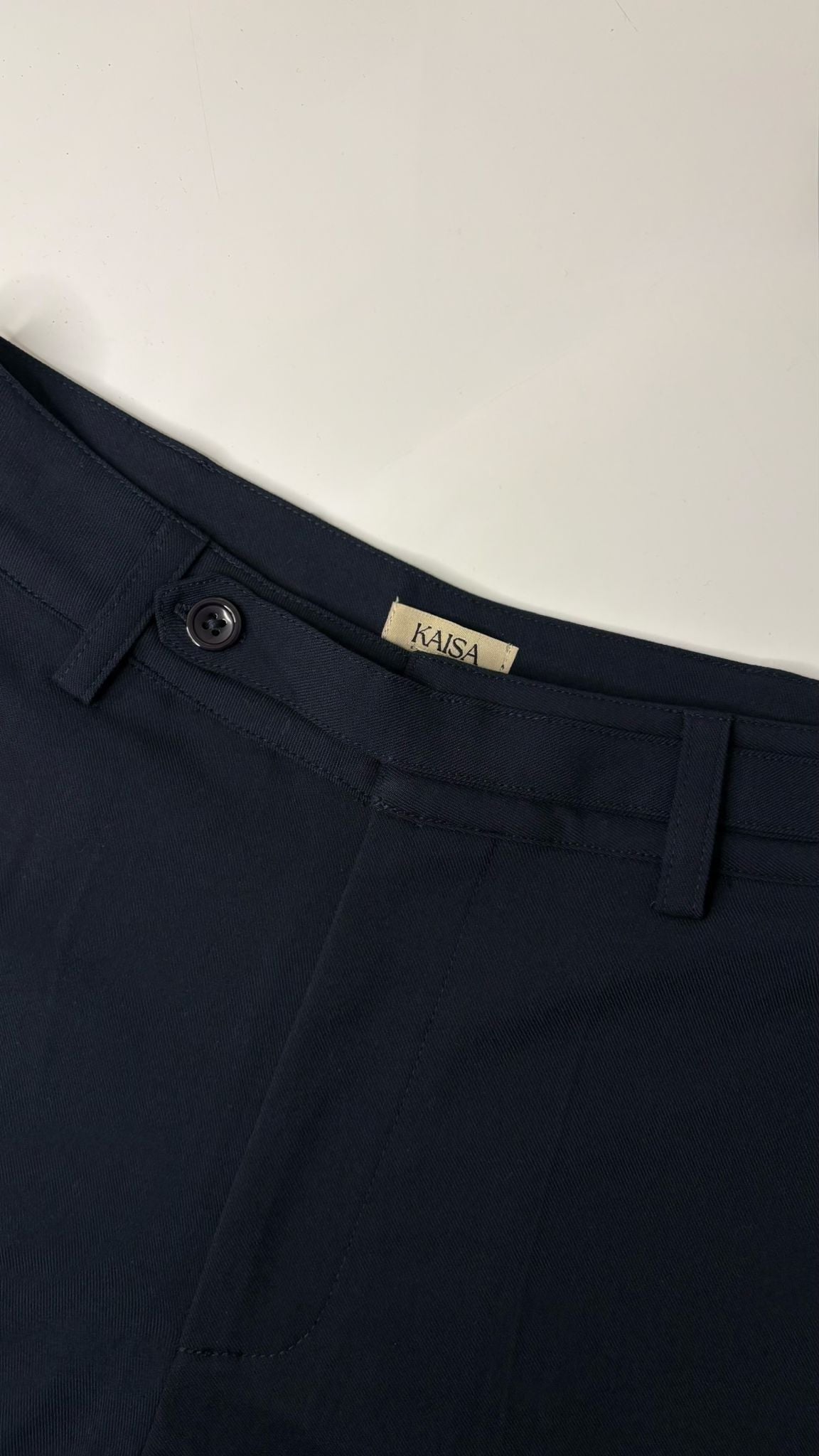 Close-up of Muse straight leg trousers in midnight blue showing waistband, button fastening and KAISA inside logo label, tailored fit for petite frames