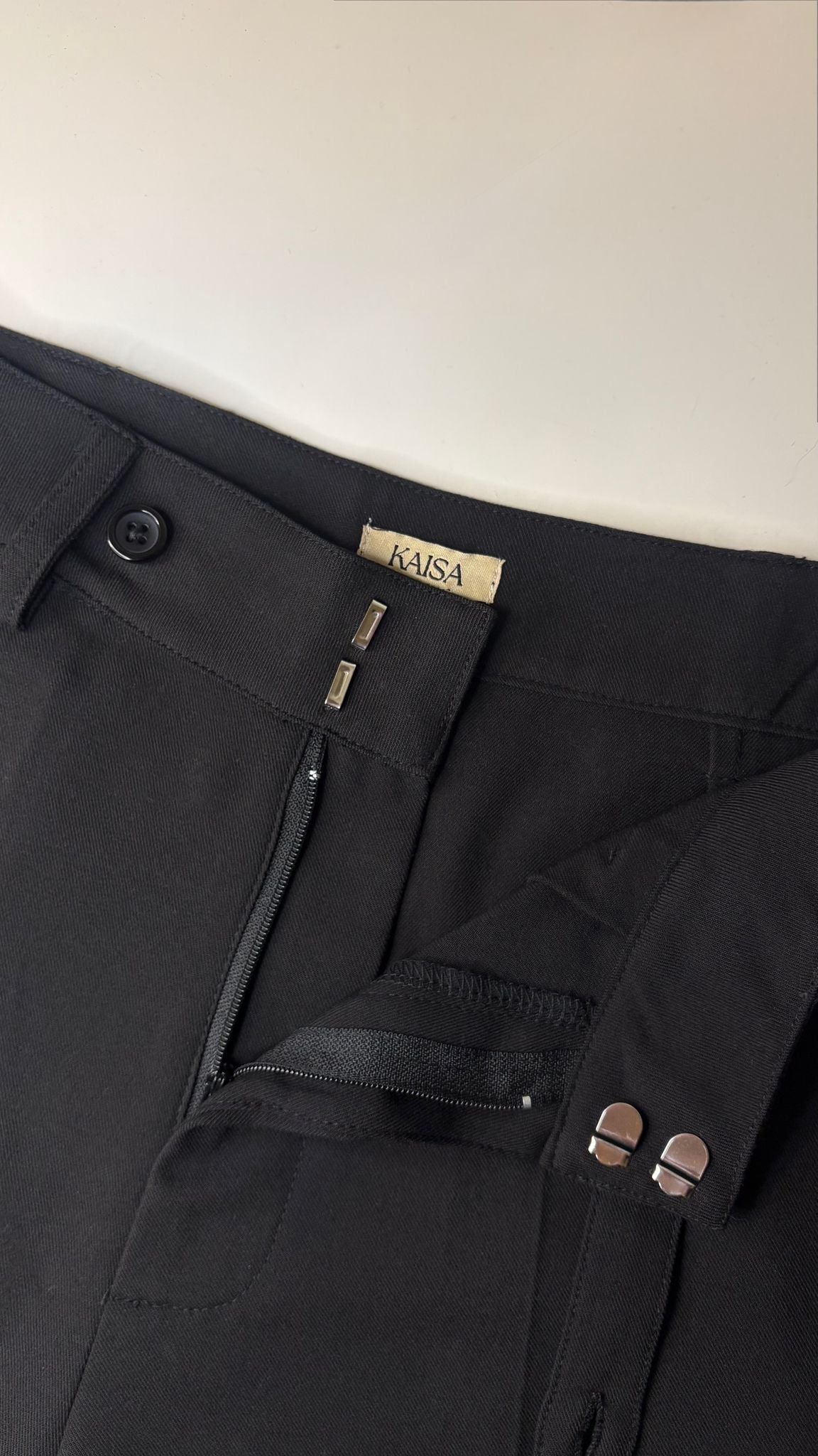 Close-up of Muse straight leg trousers in noir black showing open fly zipper detail, tailored fit for petite frames