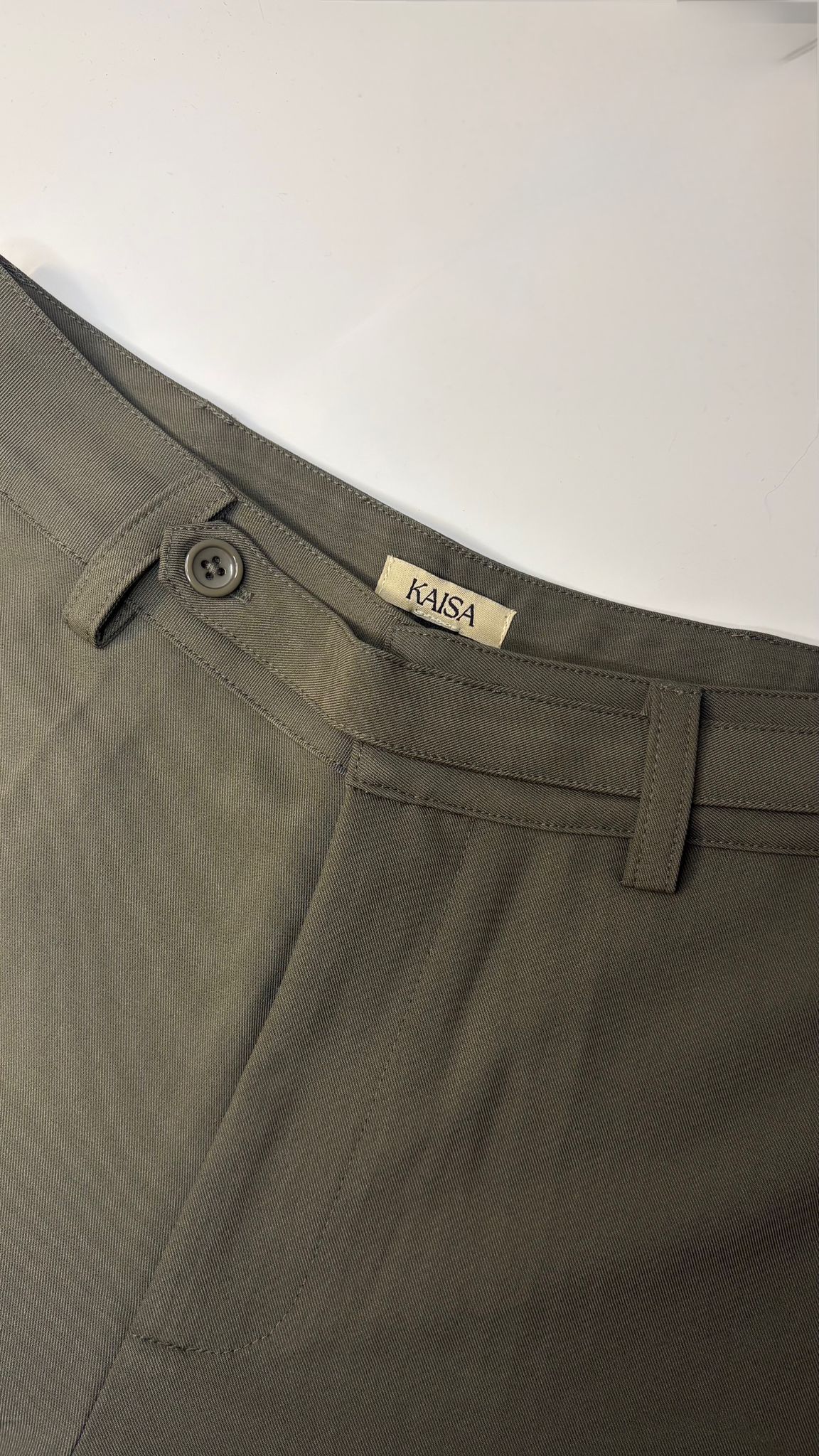 Close-up of Muse straight leg trousers in olive green showing waistband, button fastening and KAISA inside logo label