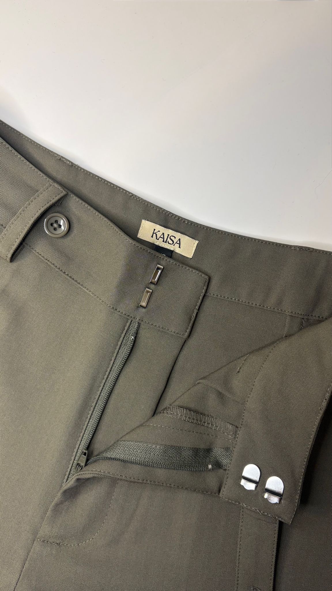 Close-up of Muse straight leg trousers in olive green showing open fly zipper detail, tailored fit for petite frames
