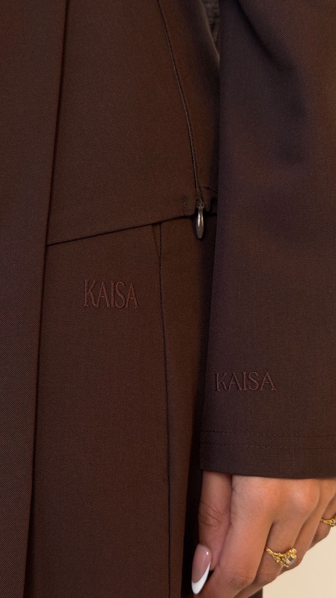 Close-up of KAISA logo detail on sleeve of Muse tailored top in coffee brown