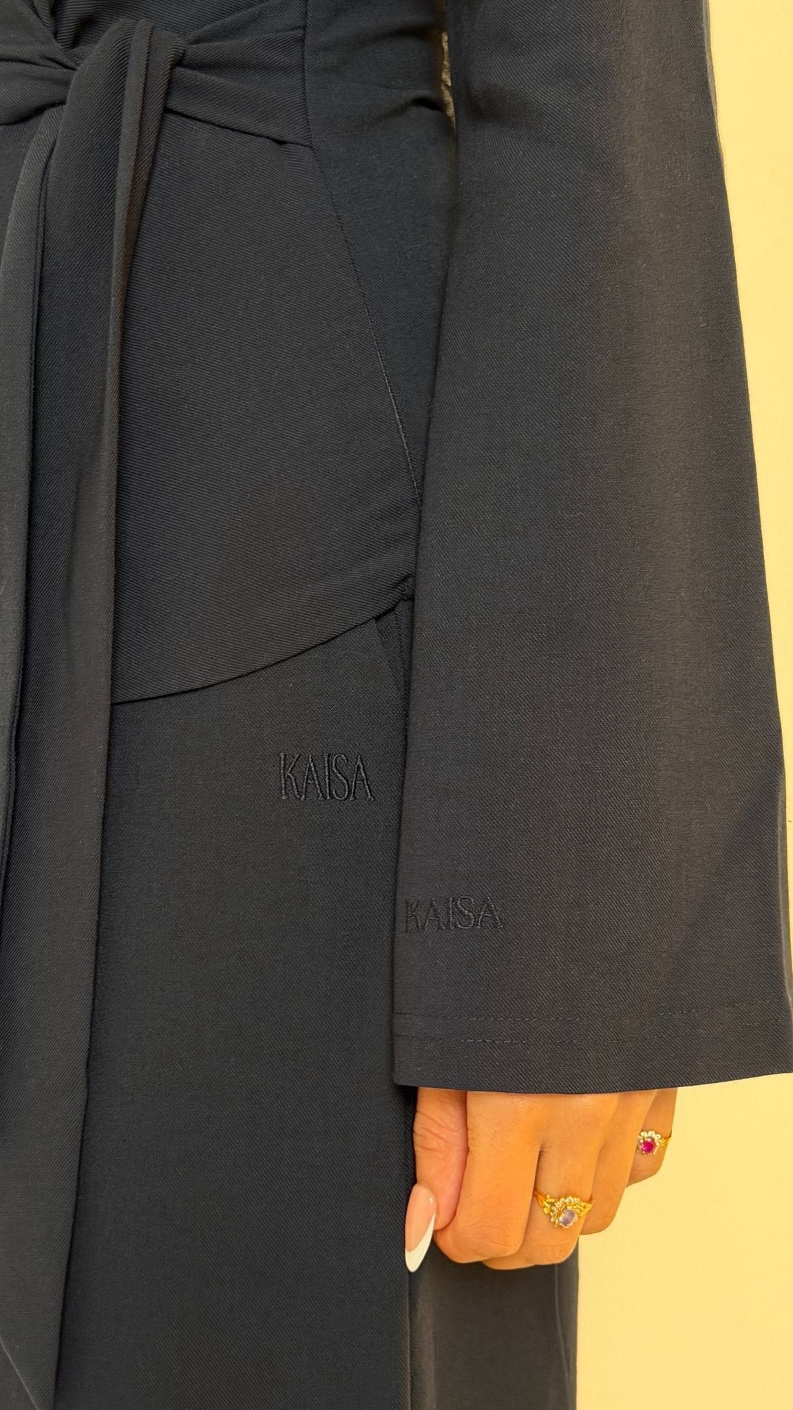 Close-up image showing KAISA logo embroidery on sleeve of Muse tailored top in midnight blue