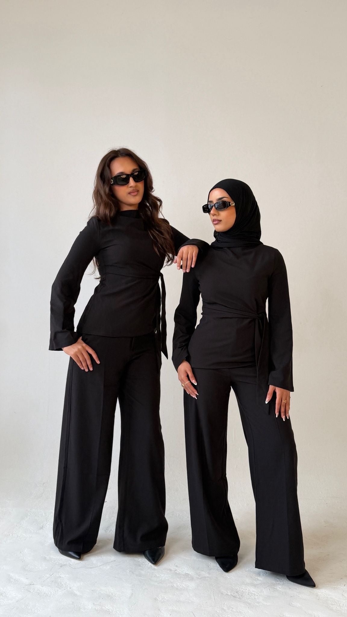 Two models facing forward wearing Muse tailored tops in noir black, designed for petite frames with structured fit