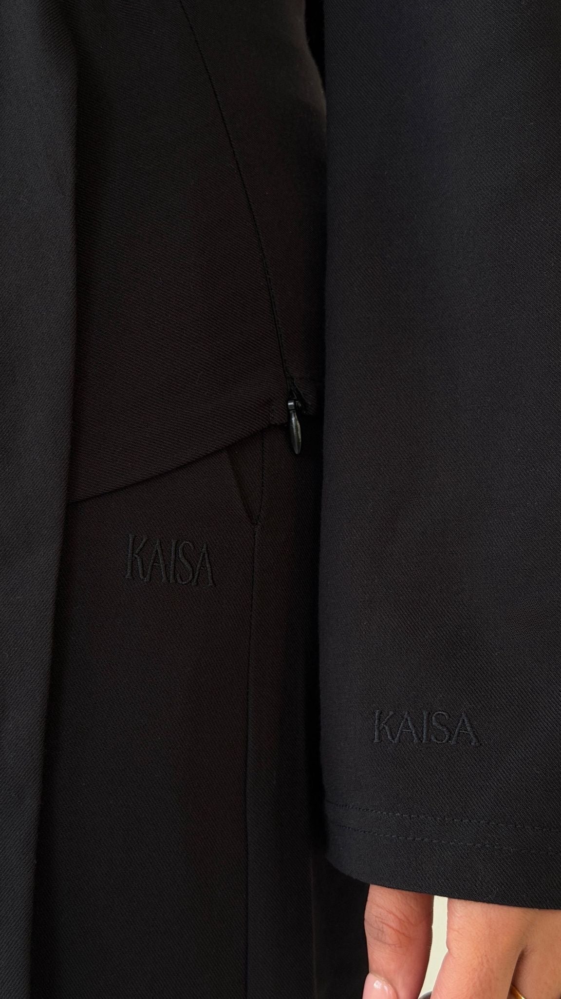 Close-up of KAISA logo detail on sleeve of Muse tailored top in noir black