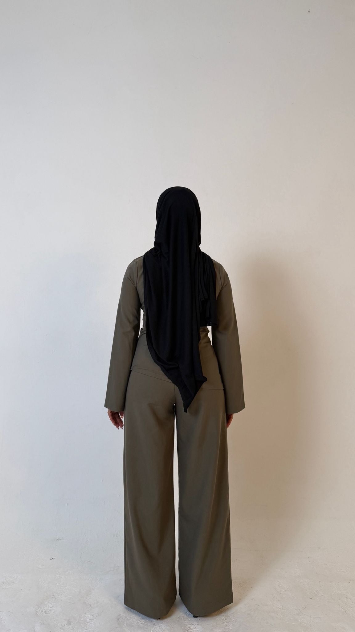 Model facing away showing back view of Muse tailored top in olive green, designed for petite frames with structured fit
